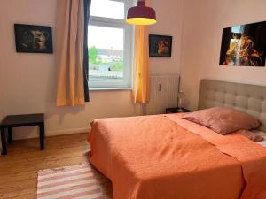 a bedroom with a bed with an orange blanket and a window at Casa Luna 6 min Hbf , Erdgeschosswohnung ,Altbau in Duisburg