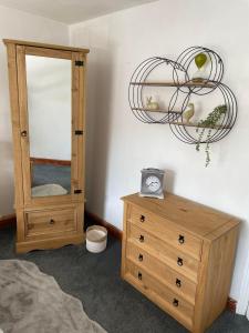 ein Schlafzimmer mit einer Kommode und einem Spiegel sowie einer Kommode mit einem Kleid in der Unterkunft The Cottage Upstairs at The Green Man, Ropsley in Ropsley