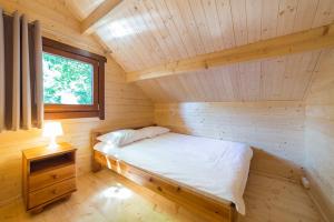 a bed in a wooden room with a window at Ośrodek Wypoczynkowy NA WYDMIE in Dziwnów