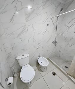 a white bathroom with a toilet and a sink at Dúplex Dorrego in Barraquero