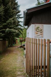 Ein Zaun neben einem Gebäude mit Schild. in der Unterkunft Domek nad Jeziorem Parzeńskim in Parzeńsko