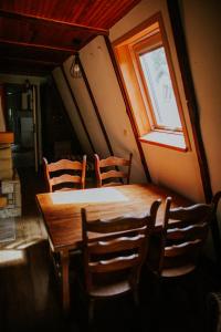 een houten tafel en stoelen in een kamer met een raam bij Domek nad Jeziorem Parzeńskim in Parzeńsko