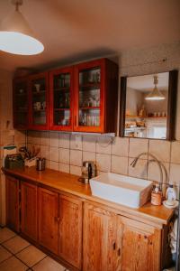 eine Küche mit Holzschränken und einem weißen Waschbecken in der Unterkunft Domek nad Jeziorem Parzeńskim in Parzeńsko