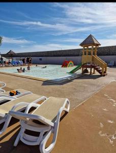 una piscina con sillas y un parque infantil en Mobil-home grau du roi vagues Océanes, en Le Grau-du-Roi