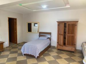 a bedroom with a bed and a wooden cabinet at Pousada MK TOUR in Pedra de Guaratiba