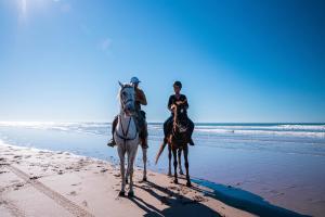 zwei Menschen reiten am Strand in der Unterkunft Villa Tazerzit comfort et hospitalité in Essaouira
