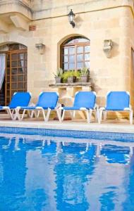 un gruppo di sedie blu accanto alla piscina di Villa Harruba a Xagħra