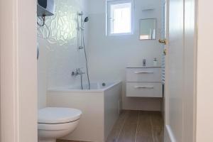a white bathroom with a toilet and a sink at Villa Keller in Balatonboglár
