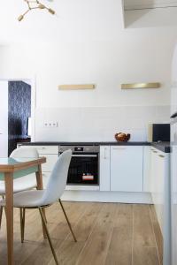 a kitchen with white cabinets and a table with a chair at Villa Keller in Balatonboglár