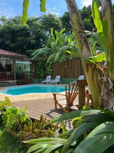 una piscina con 2 sillas y una mesa en Pousada Banana Verde, en Ilhabela