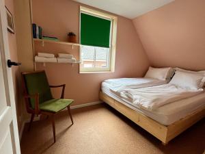1 dormitorio pequeño con 1 cama y 1 silla verde en Red Cat in Bed, en Eenrum