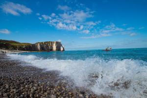 een boot in de oceaan naast een rotsachtig strand bij Escapade au Roc de Picchu in Étretat
