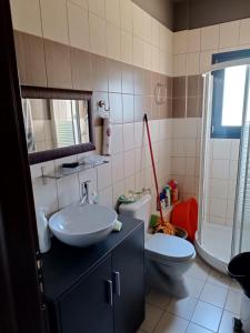 uma casa de banho com um lavatório, um WC e um espelho. em Villa Anna em Amaliapoli