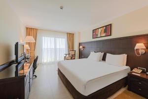 Cette chambre comprend un grand lit et une télévision. dans l'établissement Crowne Plaza Antalya, an IHG Hotel, à Antalya