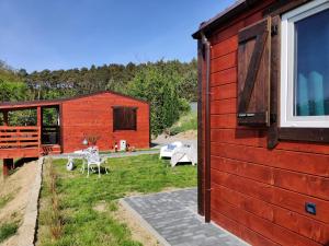 een rood gebouw met een tuin met een patio bij Domus Mare Tiny House 1 in Wisełka