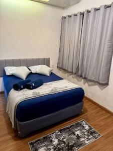 uma cama com lençóis e almofadas azuis num quarto em Casa aconchegante em Araxá em Araxá