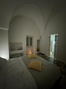 - une chambre blanche avec un grand lit et des oreillers jaunes dans l'établissement La Casa Shabby Chic, à Matino