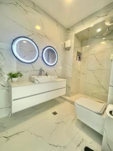 La salle de bains blanche est pourvue d'un lavabo et d'un miroir. dans l'établissement Durres Currila Modern Luxury STUNNING Beach Views, à Durrës
