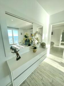 une chambre blanche avec un miroir et des fleurs sur un comptoir dans l'établissement Durres Currila Modern Luxury STUNNING Beach Views, à Durrës
