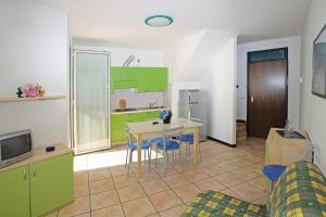 eine Küche mit grünen Schränken sowie einem Tisch und Stühlen in der Unterkunft Wohnungen in Ferienanlage in Bibione