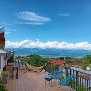 Un balcón con sillas, una hamaca y montañas. en Hestia - Hotel, Wine and View en Tʼelavi