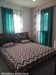 a bedroom with a large bed with green curtains at Résidence Ahitantsoa Majunga in Mahajanga