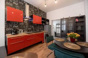 una cucina con armadi rossi e un tavolo con sedie di Cozy studio near Old Town a Toruń