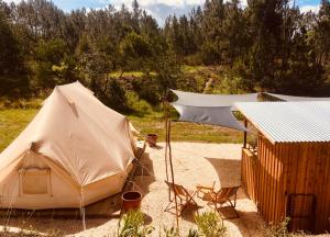羅吉爾的住宿－Tente Glamping nature et océan, Rogil，一座建筑旁边的沙子上的一个帐篷和椅子