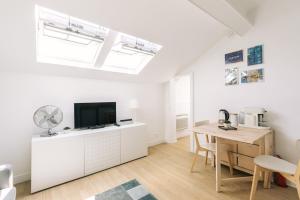 a white living room with a table and a tv at GuestReady - Radiance in comfort near Paris in Saint-Cloud +11 photos
