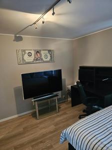 a bedroom with a bed and a flat screen tv at Montana Guest House. in Lillestrøm