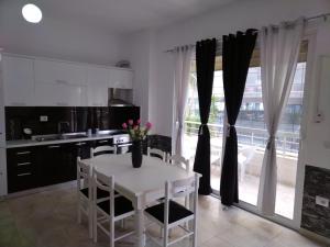 a kitchen with a white table with a vase of flowers on it at Apartment TEONA in Sarandë