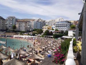 a beach with umbrellas and people in the water at Apartment TEONA in Sarandë