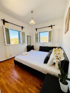 a bedroom with a large bed and two windows at Serenity House Ornos in Ornos
