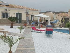 einen Garten mit Stühlen, einem Pool und einem Haus in der Unterkunft Villa Paz - Villa Familiar para 6 con piscina, AC, Wifi y parking in Arboleas