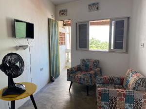 ein Wohnzimmer mit einer Couch, einem Sessel und einem Fernseher in der Unterkunft Casa da Pedra in Bezerros