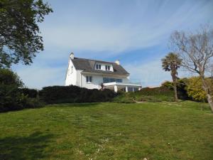 a white house on a hill with a green field at Maison avec vue sur Morgat in Crozon