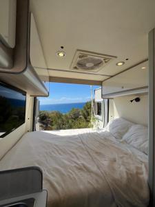 una cama en la parte trasera de una caravana con vistas al océano en Beautiful Campervan (Mallorca), en Sant Francesc