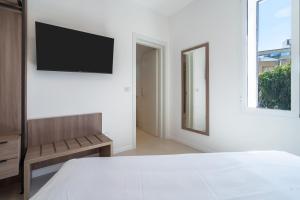 a white bedroom with a television on a wall at Dimore delle Zagare Molo in Syracuse
