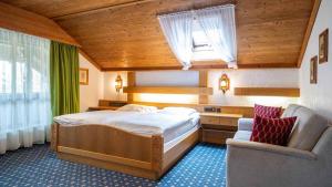 Hotel Alpina في هاغنو: غرفة نوم بسرير وكرسي في غرفة