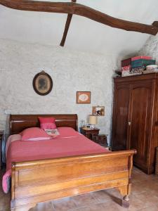 sypialnia z drewnianym łóżkiem z czerwoną pościelą w obiekcie Les Chaises w mieście Raizeux