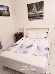 a bed in a bedroom with a poster on the wall at Appartement en résidence avec piscine in Le Gosier