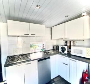 a white kitchen with white cabinets and a sink at Nettes Ferienhaus in Wervershoof mit Terrasse, Garten und Grill in Wervershoof +14 photos
