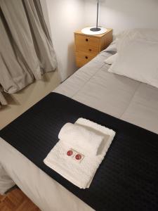 a bed with a towel and two red buttons on it at Hermoso Apartamento en Edificio Saint Michel in Córdoba