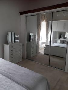 トルーンにあるHome in Troon, South Ayrshireの白いベッドルーム(大きな鏡、ベッド付)