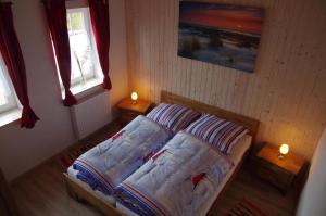 una piccola camera da letto con un letto e due finestre di Ferienvilla "Lara's Olle Warft" a Krummhörn