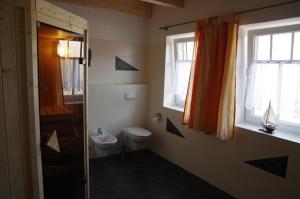 un bagno con servizi igienici e lavandino e 2 finestre di Ferienvilla "Lara's Olle Warft" a Krummhörn