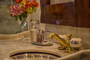 ein Waschbecken mit einer Vase aus Blumen und einem Glas in der Unterkunft A Casa da Fazenda in Santo Antônio do Pinhal