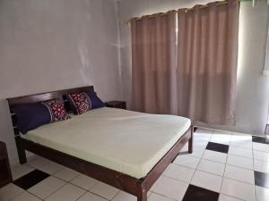 a bed sitting in a room with a curtain at Bungalow chez Mouch Nosy-Be 2 in Nosy Be