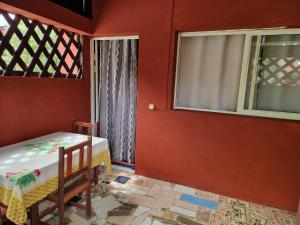 une chambre rouge avec une table et une fenêtre dans l'établissement Bungalow chez Mouch Nosy-Be 2, à Nosy Be