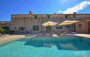 uma piscina com dois guarda-sóis e um edifício em Nettes Ferienhaus in Ses Cadenes mit Privatem Pool em Llucmajor